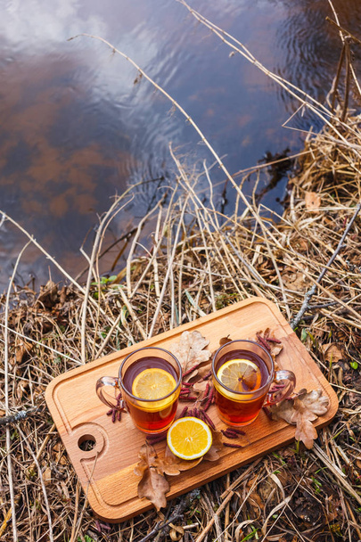 Red tea with lemon in glass mugs on the nature. - Foto, afbeelding