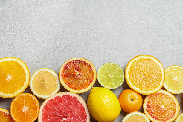 Different citrus fruits on grey background, flat lay. Space for text - Foto, Imagem