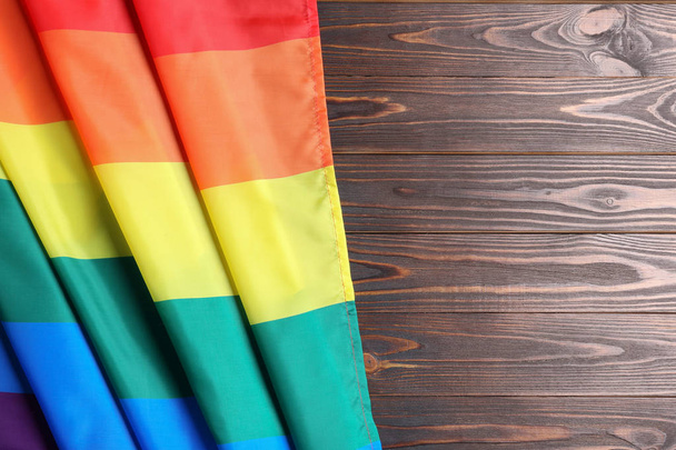 Bright rainbow gay flag on wooden background, top view with space for text. LGBT community - Foto, Imagen
