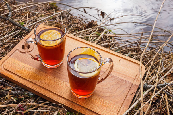 Red tea with lemon in glass mugs on the nature. - Foto, imagen
