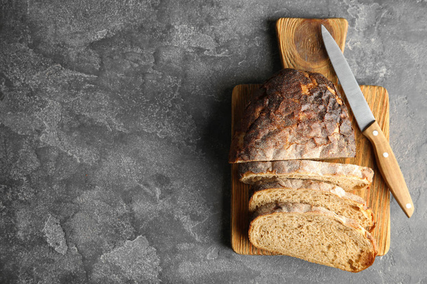 Board with bread and knife on grey background, top view. Space for text - Foto, Imagem