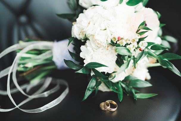 Beautiful toned picture with wedding rings against the background of a bouquet of flowers - Valokuva, kuva