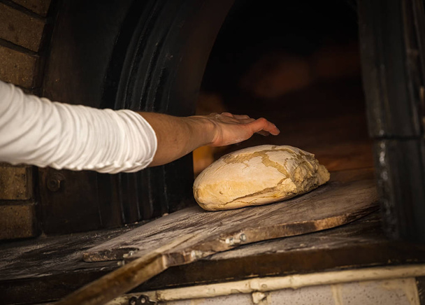 Egy pékség fatüzelésű kemencében sült kenyér előállítása. - Fotó, kép