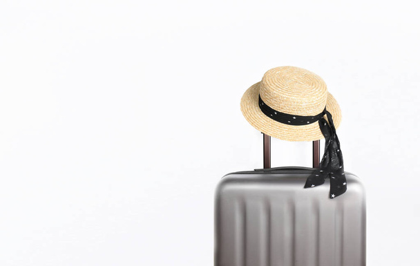 Suitcase with hat on light grey background with place for text. Minimal creative travel concept - Foto, Bild