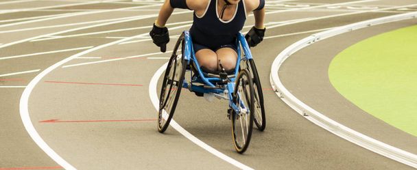 Corrida de atleta de cadeira de rodas em pista coberta
 - Foto, Imagem