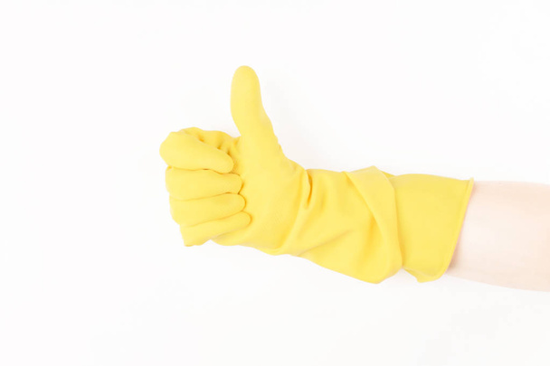 Close up of female hand in yellow protective rubber glove showing thumbs up sign against white background - Valokuva, kuva