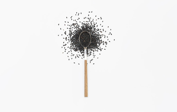 Black sesame seeds in a spoon isolated on white. Flat lay. Top view - 写真・画像
