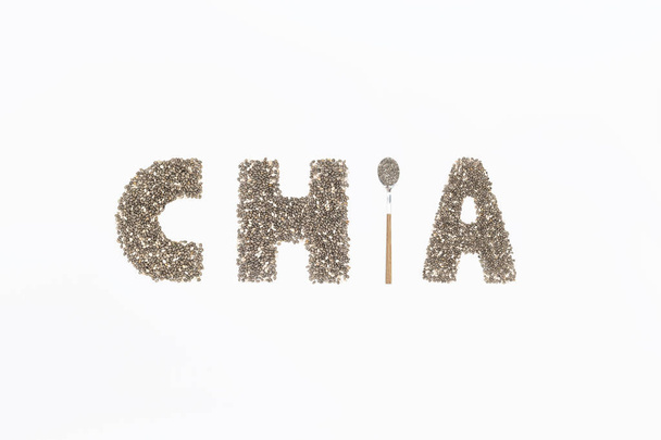 Chia word made from chia seeds with spoon full of seed on white background. Flat lay. Top view - Photo, Image