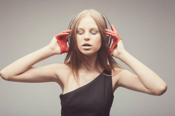 Fashion pretty girl listening music with headphones, wearing red - Fotografie, Obrázek
