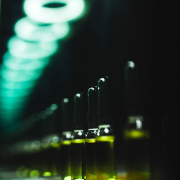 Glass vials for medicine on a black background. drug production. artistic dark filter. - Zdjęcie, obraz