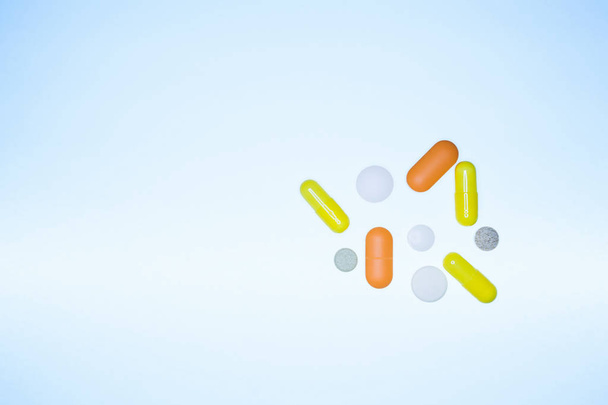 colored pills, capsules, vitamins flying out of a vial on a blue background, life concept, closeup, copy space - Foto, Imagen