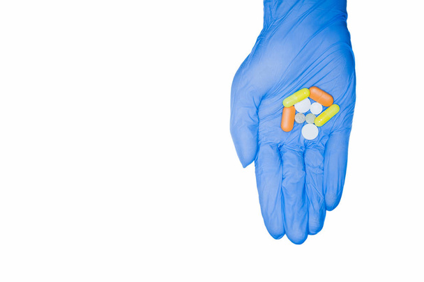 Hand in glove holding pills on white background isolate - Фото, изображение