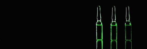 Pharmaceutical drugs banner. ampoules with green contents on a black background - Фото, зображення