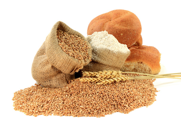 Blé cru en grains, farine, blés entiers et pains de blé entier dans des sacs en toile de jute sur blanc
. - Photo, image