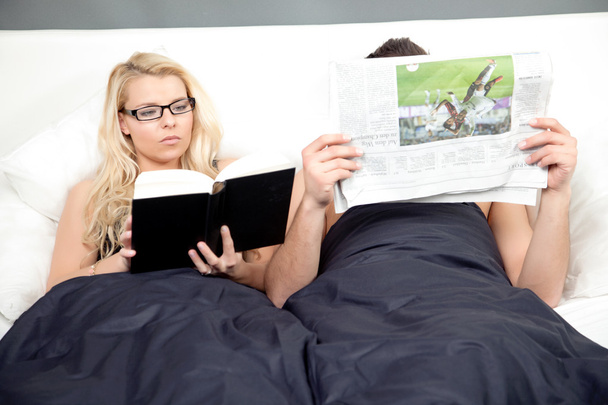 Jeune couple couché dans le lit lecture
 - Photo, image