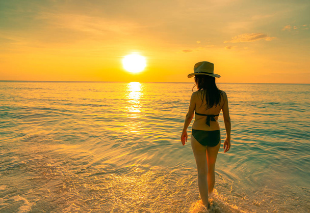 Silhouette donna adulta a piedi al mare tropicale con bel cielo al tramonto sulla spiaggia paradisiaca. Happy girl indossare bikini e cappello di paglia rilassante vacanza estiva. Viaggi di vacanza. Vibrazioni estive. La vita va avanti
. - Foto, immagini