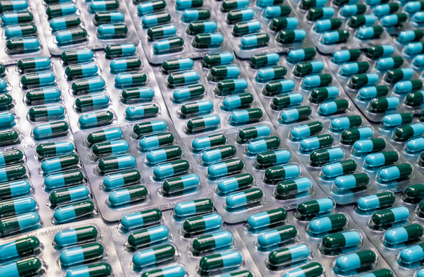 Primeros planos píldoras de la cápsula antibiótica verde-azul en blister. Resistencia a los antimicrobianos. Industria farmacéutica. Salud global. Antecedentes farmacéuticos. Productos farmacéuticos. Cápsula de amoxicilina
 - Foto, imagen