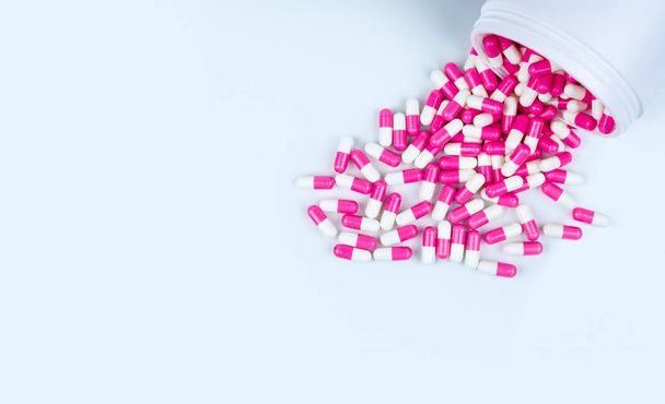 Рожево-білі таблетки антибіотиків поширюються з білої пластикової пляшки ліків. Концепція стійкості до антибіотиків. Використання антибіотиків. Глобальна охорона здоров'я. Фармацевтичний фон. Фармацевтична промисловість
. - Фото, зображення