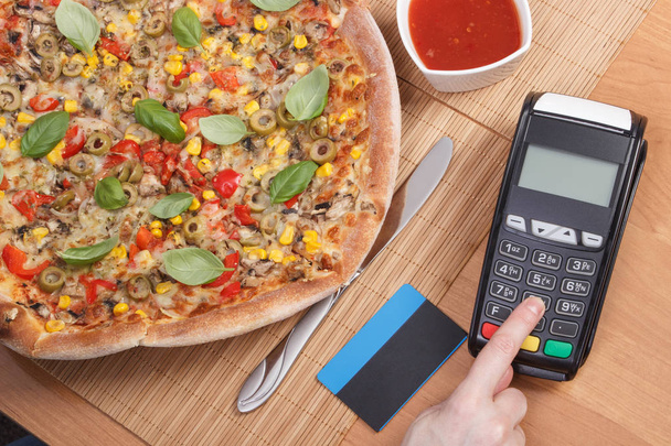 Using payment terminal for paying in restaurant, enter personal identification number, vegetarian pizza - Фото, зображення
