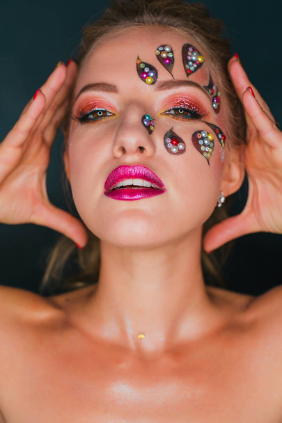 Beautiful young woman with flower face art. Spring makeup. Creative woman holiday make-up with sparles and decorative crystals - Photo, Image