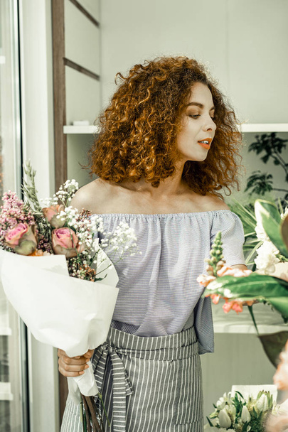 Curly appealing florist wearing open shoulder blouse working hard - Zdjęcie, obraz