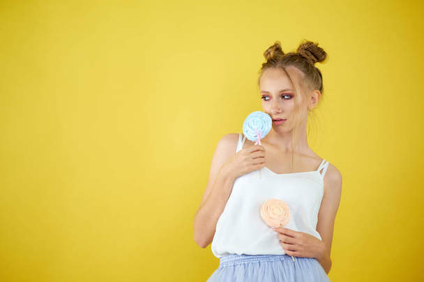 young girl with candy on a yellow bright background. beautiful make-up, - Foto, afbeelding
