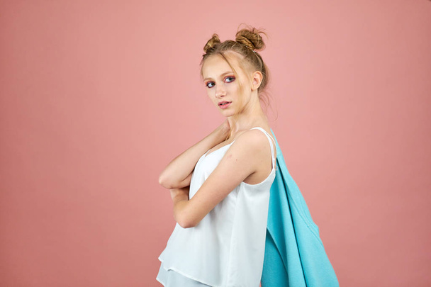 modelo joven feliz posando en el estudio sobre un fondo rosa en ropa de primavera. moda para adolescentes, colores brillantes. capa de turquesa
 - Foto, imagen