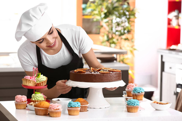Joven pastelera con dulces en la cocina
 - Foto, imagen