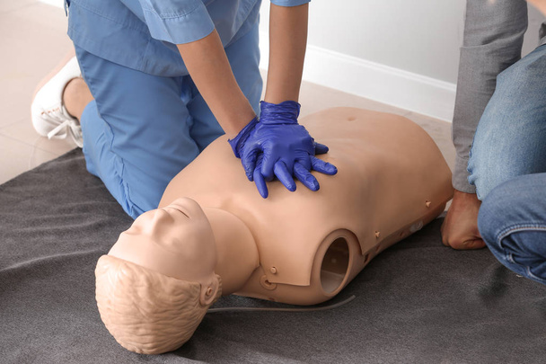 Инструктор, демонстрирующий искусственное дыхание на манекене на курсах первой помощи
 - Фото, изображение