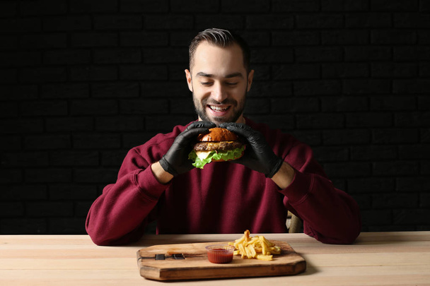 Ember eszik ízletes burger és hasábburgonyával, asztal - Fotó, kép