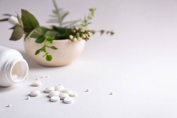 Garrafa com pílulas e ervas no fundo claro
 - Foto, Imagem