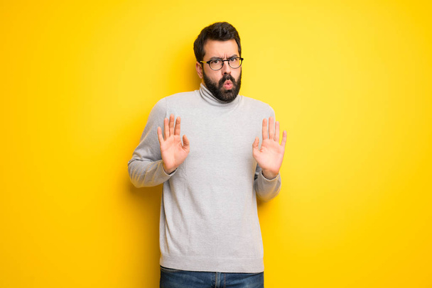 Man with beard and turtleneck making stop gesture with both hands - Photo, Image