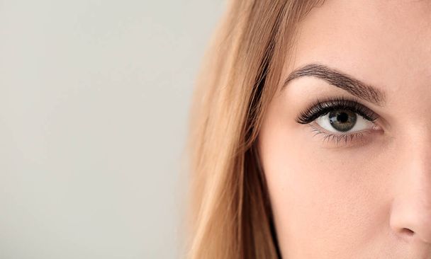 Young woman with beautiful eyelashes on light background, closeup - Photo, Image