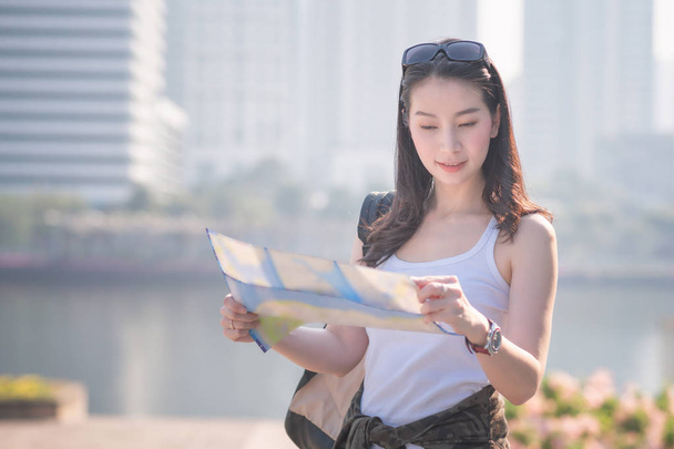 Hermosa mujer turista asiática sola mirando el mapa en busca de turistas punto de interés. Viajes de vacaciones en verano
. - Foto, Imagen