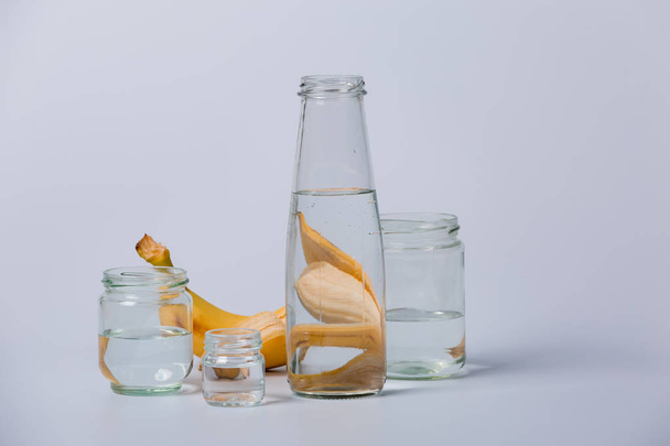 Glass transparent bottles of different sizes from large to small on a white background. Banana juice, fresh juice, fruity. - Fotó, kép