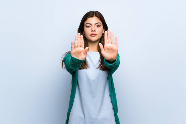 Nastolatek dziewczyna nad niebieską ścianą podejmowania gest stop i rozczarowany - Zdjęcie, obraz