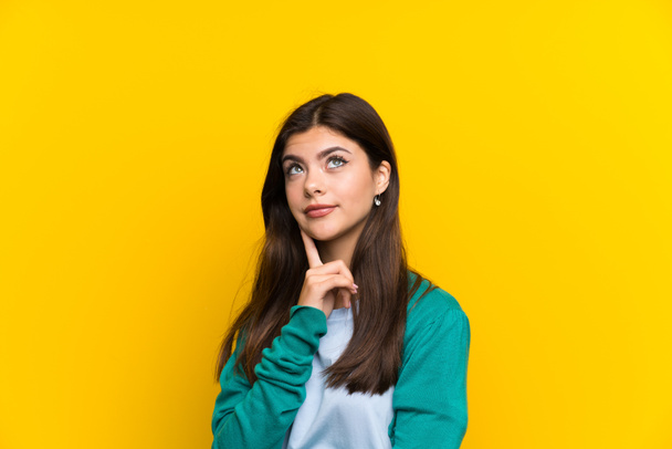 Adolescente chica sobre amarillo pared pensando en una idea
 - Foto, imagen