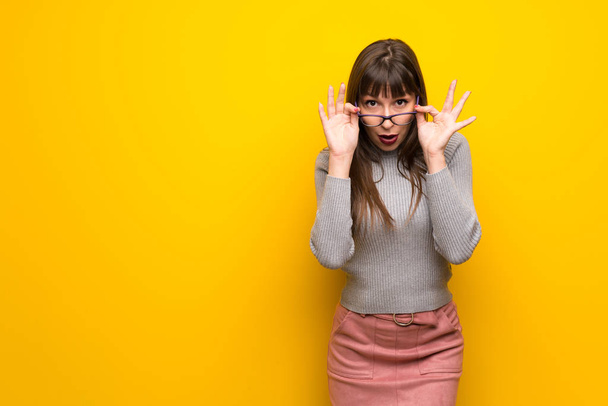 Woman with glasses over yellow wall with glasses and surprised - Photo, Image