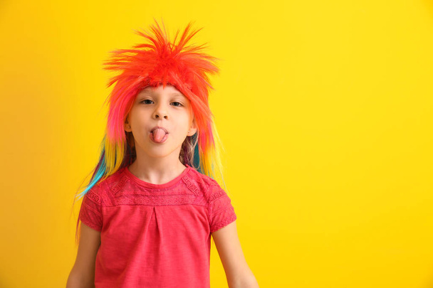 Funny klein meisje in pruik tonen tong op kleur achtergrond. April Fools ' dag viering - Foto, afbeelding