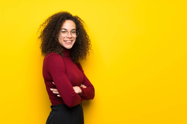 Dominican woman with turtleneck sweater keeping the arms crossed in lateral position while smiling - Фото, изображение