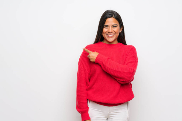 Молодая колумбийская девушка в красном свитере указывает в сторону, чтобы представить продукт
 - Фото, изображение