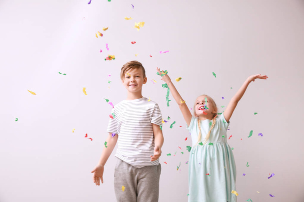 Cute little children and falling confetti on light background - Photo, Image