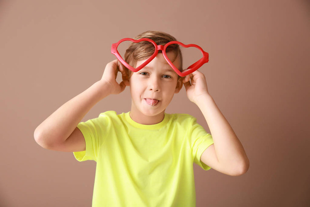 Funny little boy with big glasses on color background - Photo, Image