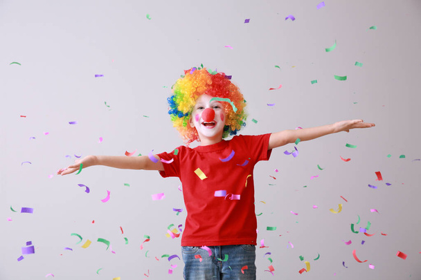kleiner Junge in lustiger Verkleidung und fallendem Konfetti auf hellem Hintergrund. Aprilscherz-Fest - Foto, Bild