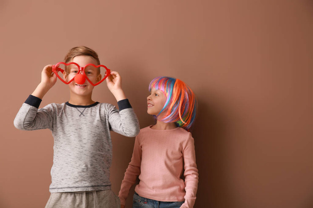 Little children in funny disguise on color background. April fools' day celebration - 写真・画像