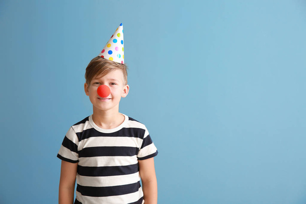 Маленький хлопчик з клоуном і вечірнім капелюхом на кольоровому фоні. квітня святкування дня дурнів
 - Фото, зображення