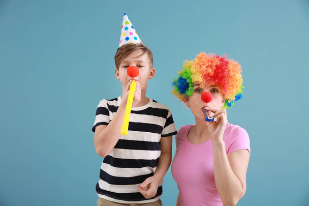 Menino e sua mãe em disfarce engraçado com assobios de festa no fundo da cor. Celebração do dia dos tolos de Abril
 - Foto, Imagem