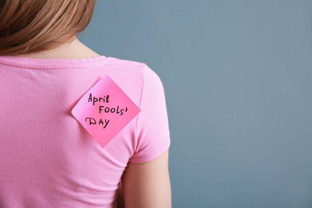 Nota pegajosa con frase "Día de los tontos de abril" en la espalda de la mujer
 - Foto, Imagen