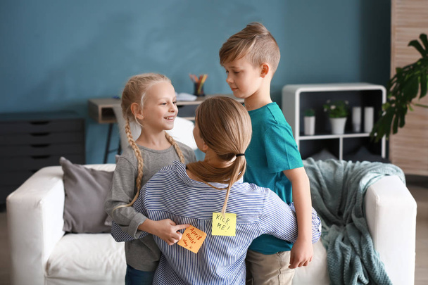 Les enfants attachent des feuilles de papier avec le texte KICK ME et AVPRIL FOOLS 'DAY au dos de leur mère
 - Photo, image