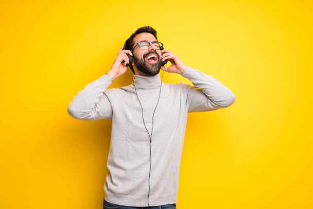 Άνθρωπος με γένια και ζιβάγκο ακούγοντας μουσική με ακουστικά - Φωτογραφία, εικόνα
